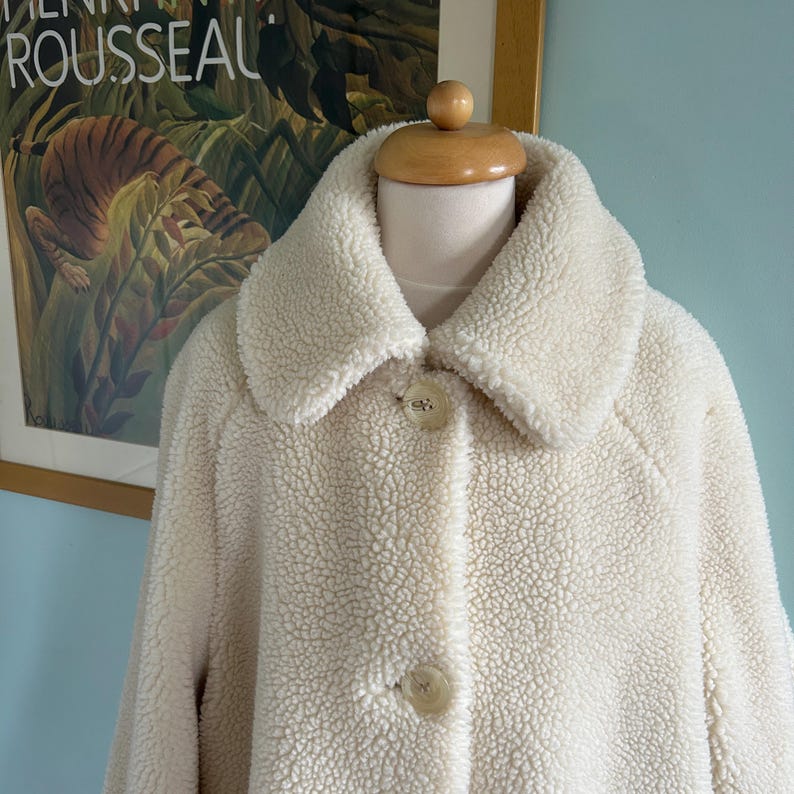 May include: A white faux fur coat with a large collar and two button closures.