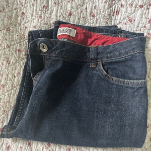 May include: A pair of dark blue denim jeans with a red and white label that says "Coast" on the waistband.