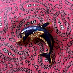 Vintage gold tone, enamel and sparkling diamanté leaping dolphin brooch.