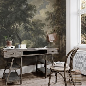 May include: A rustic wooden desk with two drawers and open shelving is set against a forest mural. A brown leather bag hangs on the wall. A potted plant and books sit on the desk, with a wooden chair nearby.