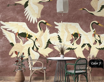 Op de afbeelding: Een rode muur met een wit plafond en een witte lamp die aan het plafond hangt. De muur is versierd met een muurschildering van witte kranen in de vlucht. Twee stoelen en een tafel staan voor de muur. De tafel is rond en heeft een zwart metalen frame. De stoelen zijn van hout en hebben een gevlochten zitting en rugleuning. De stoelen zijn groen en bruin. De tekst "Color F" staat op de muur.