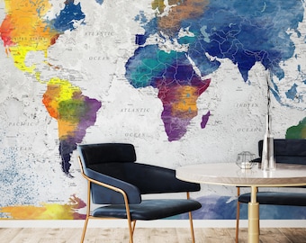 Könnte beinhalten: Ein Wandbild mit einer Weltkarte in Aquarelloptik in Gelb-, Orange-, Blau-, Lila- und Grüntönen auf einem strukturierten weißen Hintergrund. Die Karte zeigt Ländernamen und Ozeanbezeichnungen in schwarzer Schrift auf den Kontinenten.