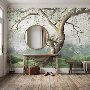 Könnte beinhalten: Ein Wandbild mit einem großen Baum mit grünen Blättern und weißen Blüten, einem runden goldgerahmten Spiegel, einem Holzkonsolentisch mit einer Vase voller Grün, einer braunen Lederaktentasche, einem Paar brauner Schuhe und einer Holzbank mit Decke.