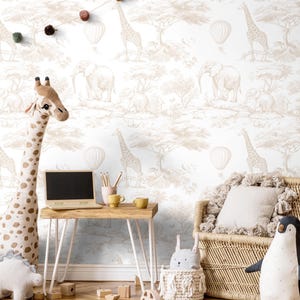 May include: A nursery with a safari theme. The wallpaper has a repeating pattern of elephants, giraffes, and hot air balloons in neutral tones. A giraffe soft toy stands near a small wooden desk with a laptop and a woven chair.