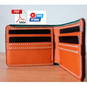 May include: Open leather wallet in shades of orange and green, with white stitching. The wallet has multiple card slots and a bill compartment. The image also includes a PDF Adobe icon and a video tutorial icon.