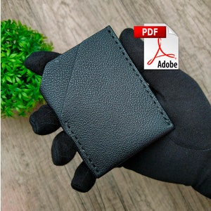 May include: Black leather wallet with a stitched edge. The wallet is folded in half and has a smooth, textured surface.