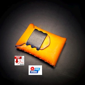 May include: Handmade orange leather card holder with a black leather flap. The card holder has a stitched border and a dark blue accent. The image also includes a PDF and video tutorial icon.
