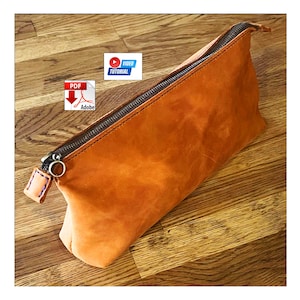 May include: A tan leather zippered pouch featuring a dark metal zipper, a circular metal pull tab, and a small leather tab with blue stitching. The image includes a PDF Adobe icon and a blue and white Video Tutorial icon overlay.