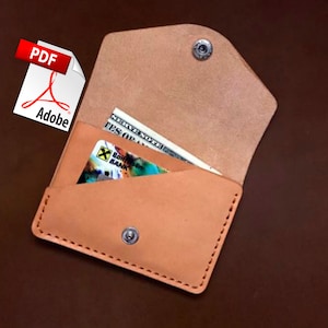 May include: A light brown leather wallet with a snap closure, holding a credit card and a paper bill. The wallet is open, revealing the contents. The Adobe PDF logo is in the upper left corner.