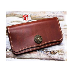 May include: A brown leather wallet with a decorative metal button clasp. The wallet is rectangular with rounded corners and features visible stitching. The leather has a rich, textured appearance. The Adobe PDF icon is in the top left corner.