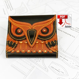 May include: A handmade leather wallet with an owl design. The wallet features a black base with a brown and black owl face stitched on the front. The owl's eyes are detailed with small rivets, and the stitching is yellow.