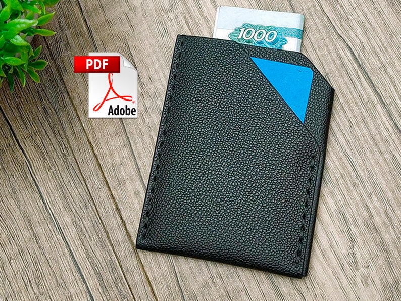 May include: Black leather wallet with a blue accent and a slot for cash. The wallet is on a wood surface. The text "1000" is visible on the cash.