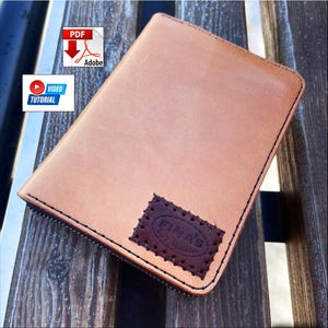 May include: A tan leather notebook cover with a dark brown rectangular patch featuring the embossed text FIMA'S Leather. The cover has black stitching along the edges and a zipper closure. Includes a PDF icon and a video tutorial icon.