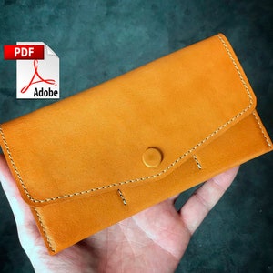 May include: A brown leather wallet with a snap closure and white stitching. The wallet is folded in half and has a small pocket on the front.
