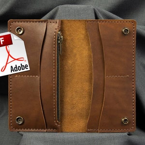 May include: Open brown leather wallet with a zipper and snap closures. The interior is a lighter shade of brown. A PDF Adobe file is in the upper left corner. The wallet is on a gray background.