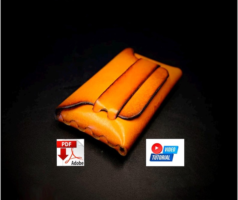 May include: A handcrafted, orange leather wallet with a flap closure. The wallet has a rich, warm color and a smooth texture. The design includes a decorative flap and a contrasting dark brown edge. The image also includes a PDF and video tutorial icon.
