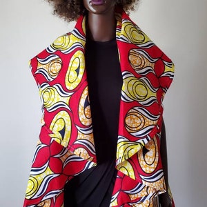 Pu&ograve; includere: Un avvolgente con motivo rosso, giallo e bianco con un design drappeggiato asimmetrico. L'avvolgente &egrave; realizzato in un tessuto morbido e leggero, perfetto per essere indossato sopra un vestito o una camicetta.