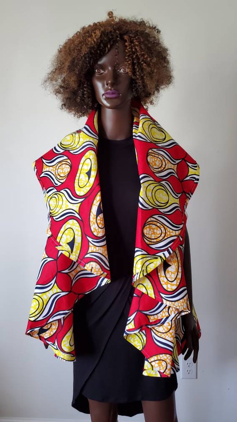 Pu&ograve; includere: Un avvolgente con motivo rosso, giallo e bianco con un design drappeggiato asimmetrico. L'avvolgente &egrave; realizzato in un tessuto morbido e leggero, perfetto per essere indossato sopra un vestito o una camicetta.