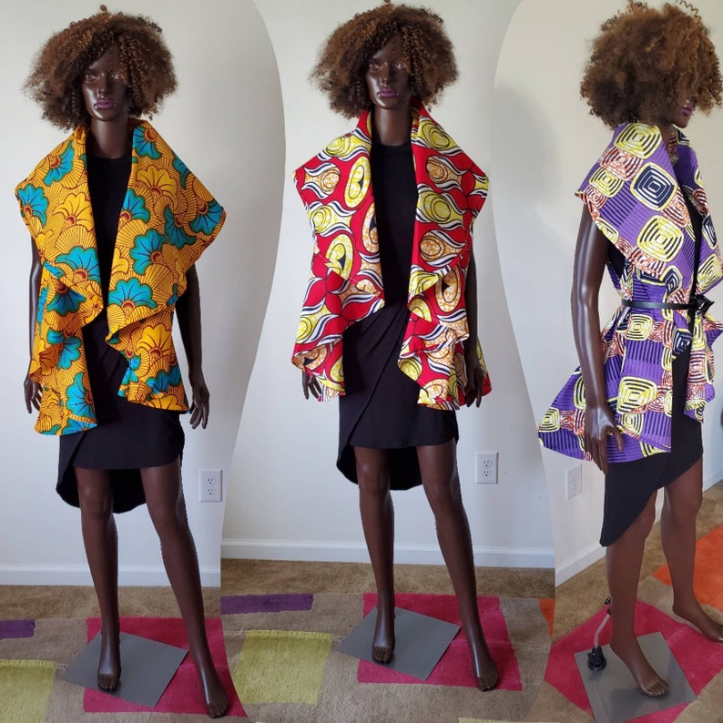 Pu&ograve; includere: Tre manichini indossano giacche senza maniche con motivi diversi. Le giacche sono realizzate in tessuto stampato africano colorato. Le giacche sono tutte di colori e motivi diversi. I manichini indossano tutti gonne nere.
