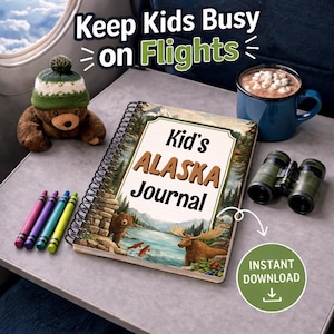 May include: A spiral-bound "Kid's Alaska Journal" with a scenic cover illustration, next to a teddy bear wearing a green and white hat, crayons, binoculars, and a mug of hot chocolate. The image includes the text "Keep Kids Busy on Flights" and "Instant Download".