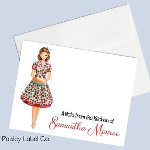 May include: A white card with a red and green illustration of a woman holding a pie. The text "A Note from the Kitchen of Samantha Monroe" is printed in red at the bottom of the card.