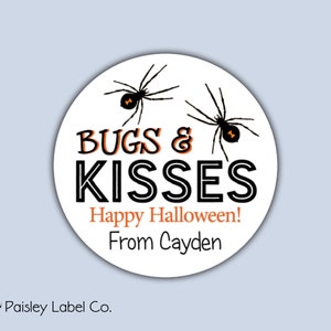 May include: Round white sticker with black and orange text that reads "Bugs & Kisses Happy Halloween! From Cayden". Two black spiders with orange abdomens are on the sticker.