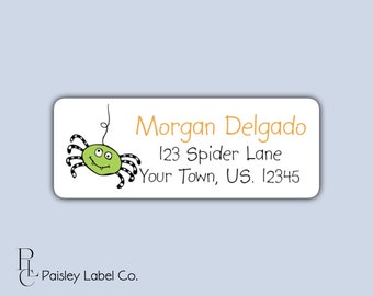 May include: A white rectangular label with a green spider with black legs and orange eyes. The label has the text "Morgan Delgado", "123 Spider Lane", and "Your Town, US. 12345" in black text.