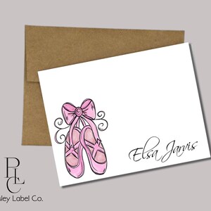 May include: A white card with a pink ballet shoe illustration and the name "Elsa Jarvis" written in black cursive.