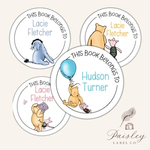 May include: Four round stickers with Winnie the Pooh characters and the text "This Book Belongs To" with names. One sticker features Eeyore, another Pooh and Piglet, and a third Pooh and Piglet. The fourth sticker has Pooh with a balloon.