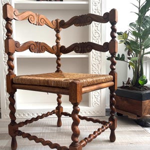 May include: An antique wooden chair with a woven seat. The chair has carved details and twisted legs. The backrest has a curved design. The chair is made of brown wood. The chair's dimensions are in centimetres.