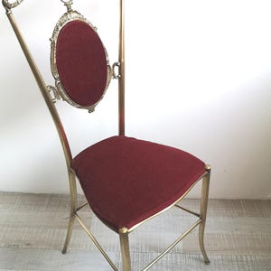 May include: A gold metal chair with a red velvet seat and a decorative back. The chair has a tall, slender design with intricate details.