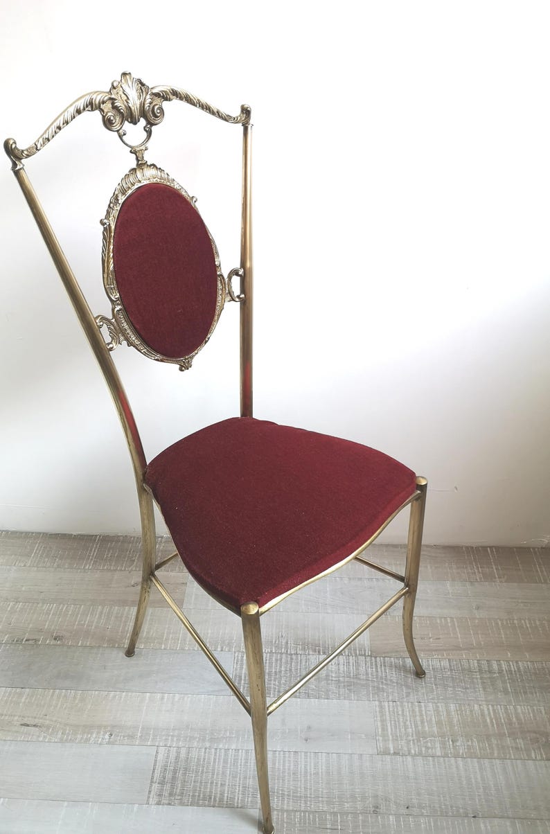 May include: A gold metal chair with a red velvet seat and a decorative back. The chair has a tall, slender design with intricate details.