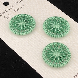 May include: Three green, handwoven buttons, each approximately 1 inch in diameter, are displayed on a white card. The card reads "Athebyne Craftworks Handwoven Buttons in the Saint Patrick design."