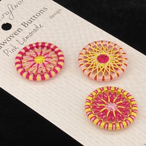 Op de afbeelding: Drie handgeweven knopen in roze en geel met een bloemenpatroon. De knopen zijn 2,5 cm in diameter en zijn handgemaakt in Fredericksburg, Virginia. Handwas wordt aanbevolen.
