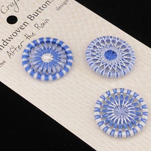 May include: Three handwoven buttons in blue and white, displayed on a card. The buttons are 1 inch in diameter and feature a detailed woven design. The card reads "Athebyne Craftworks" and "Handwoven Buttons in the After the Rain."