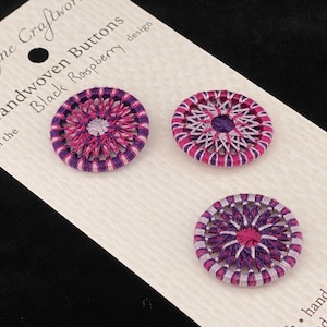 May include: Three handwoven buttons in a black raspberry design. The buttons are 1 inch in diameter and are made of purple and pink thread.