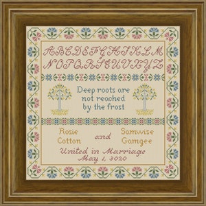 May include: A framed cross-stitch sampler with a floral border. The sampler features the alphabet, a quote about deep roots, and the names Rosie Cotton and Samwise Gamgee, along with the text "United in Marriage" and the date "May 1, 3020".