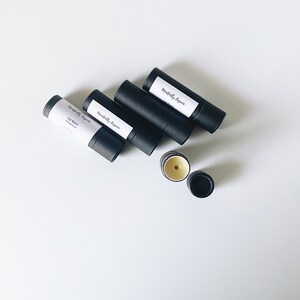 May include: Four black tubes of lip balm with white labels that read "Mindfully Organic" and "Lip Balm Peppermint". One tube is open and shows the lip balm inside.