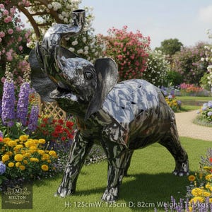 May include: A large, metallic elephant sculpture with its trunk raised, standing on a grassy lawn surrounded by flowers. The sculpture is made of reflective metal and measures 125cm high, 125cm wide, and 82cm deep, weighing 11.5kg. The sculpture has a unique, patchwork design.