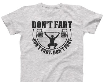 Puede incluir: Una camiseta gris con un gráfico negro de una persona levantando una barra. El gráfico está dentro de un círculo con el texto "Don't fart, Don't fart" alrededor.
