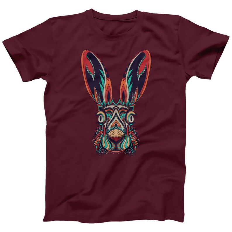 May include: A maroon t-shirt with a colorful, intricate design of a rabbit's face. The design features a variety of colors, including orange, blue, green, and yellow.