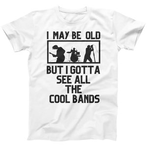 K&ouml;nnte beinhalten: Wei&szlig;es T-Shirt mit schwarzem Text, der "I may be old but I gotta see all the cool bands" lautet. Der Text ist von einem schwarzen Rechteck umgeben. Im Rechteck befindet sich eine schwarze Silhouette einer Band, die Musik spielt.