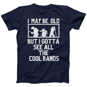 K&ouml;nnte beinhalten: Marineblaues T-Shirt mit wei&szlig;em Text, der "I may be old but I gotta see all the cool bands" lautet. Der Text ist von einem wei&szlig;en Rechteck eingerahmt. Im Rechteck befindet sich eine Silhouette einer Band, die Musik spielt.