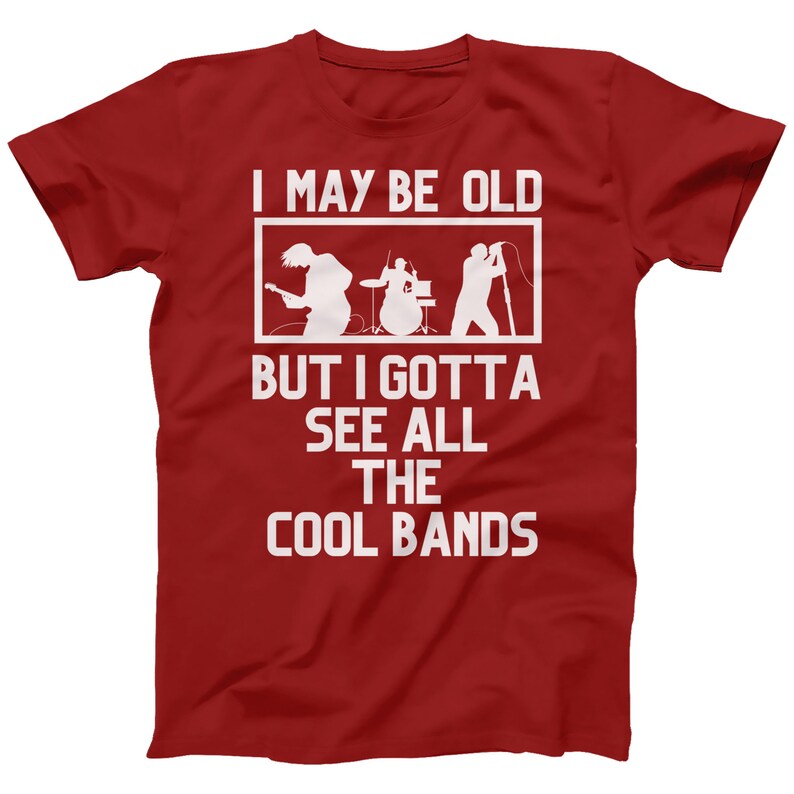 K&ouml;nnte beinhalten: Rotes T-Shirt mit wei&szlig;em Text, der "I may be old but I gotta see all the cool bands" lautet. Der Text ist von einem wei&szlig;en Rechteck umgeben. Im Rechteck befindet sich eine Silhouette einer Band, die Musik spielt.