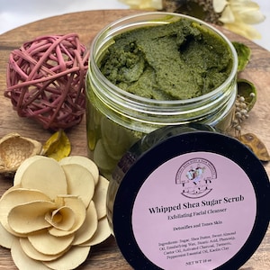 May include: A green whipped shea sugar scrub in a black jar with a pink label that reads "Whipped Shea Sugar Scrub Exfoliating Facial Cleanser Detoxifies and Tones Skin" and "Ingredients: Sugar, Shea Butter, Sweet Almond Oil, Emulsifying Wax, Stearic Acid, Phenonip, Castor Oil, Activated Charcoal, Turmeric, Peppermint Essential Oil, Kaolin Clay NET WT 10 oz".
