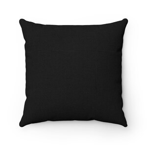 Puede incluir: Una almohada cuadrada negra con una superficie de tela texturizada.