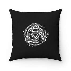 Puede incluir: Almohada de color negro y blanco con un dise&ntilde;o geom&eacute;trico de un triskel, un s&iacute;mbolo de nudo celta, rodeado de c&iacute;rculos y puntos.
