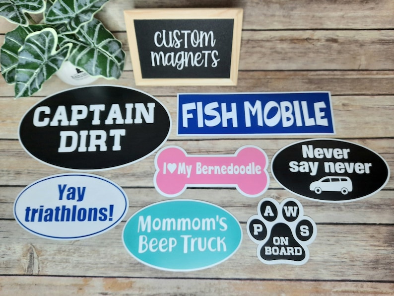 Pu&ograve; includere: Un set di otto magneti ovali e a forma di osso con varie frasi e disegni. I magneti sono neri, blu, rosa, bianchi e turchese. Le frasi includono "Captain Dirt", "Fish Mobile", "Never Say Never", "I &hearts; My Bernedoodle", "Yay Triathlons!", "Mommom's Beep Truck" e "Paws On Board".