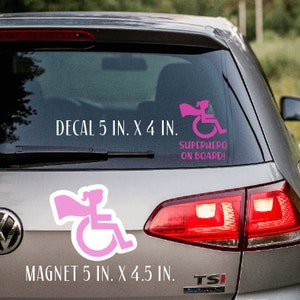 Pode incluir: Um conjunto de decalques e &iacute;m&atilde;s para carro com um super-her&oacute;i de cadeira de rodas rosa. O decalque e o &iacute;m&atilde; medem 5 polegadas por 4 polegadas e 5 polegadas por 4,5 polegadas, respectivamente. O texto no decalque diz "Superhero on Board!"