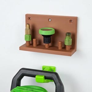 May include: A brown wall-mounted organizer with various nozzles and fittings. The organizer has a shelf with several brass, black, and green components. A green and black handle is visible below.
